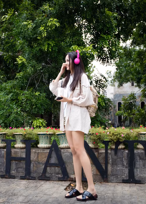 Hoa hậu Việt Nam 2006 kết hợp trang phục với phụ kiện ba lô, tai nghe màu hồng đáng yêu.