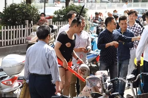 Bộ đồ màu đen bó sát được cắt, khoét, đục thủng đúng phần ngực của chú rể, phía dưới, một chiếc quần lót màu đỏ rực rỡ được lồng phía ngoài quần đùi.