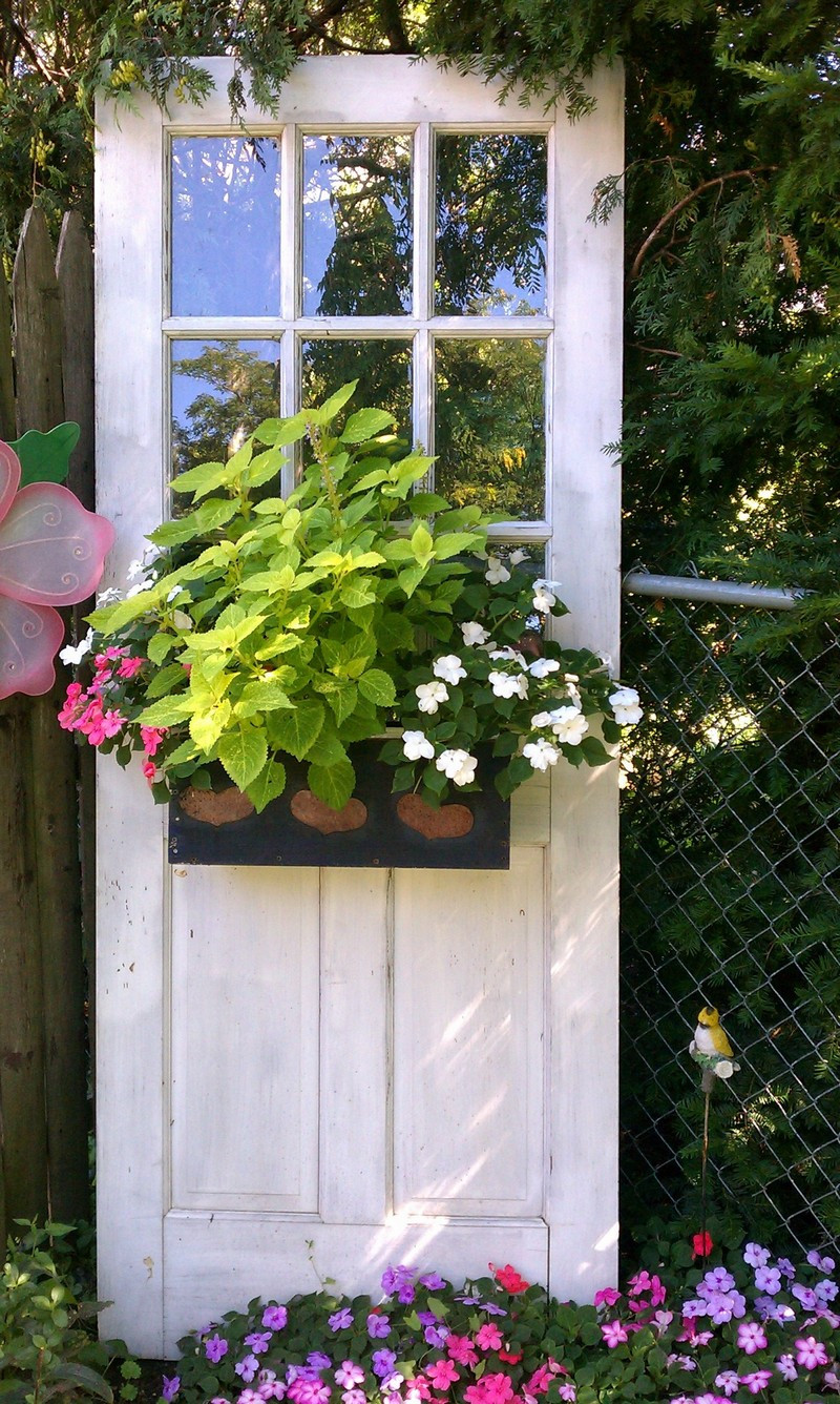  4. Vườn đứng xanh tốt: Một tác dụng khác của cánh cửa cũ là trở thành những khuôn giá trồng cây hay rau củ loại nhỏ. Bạn có thể khoét những lỗ tròn trên cửa gỗ liền hay dùng vải bao chứa đất trồng trong những cửa gỗ chia ô nhỏ. Thêm phần cố định đất trồng ở mặt sau cửa, để nghiêng hay dựng cánh cửa thẳng đứng trên hàng rào, bạn vẫn có một góc xanh bắt mắt.