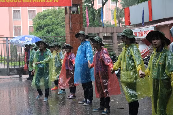 Các tình nguyện viên nắm tay nhau đứng trong mưa làm nhiệm vụ.