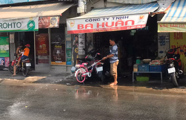 Người dân liên tục tưới nước để làm mát nhiệt độ vì nắng nóng gây oi bức, khó chịu.