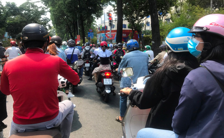 Người dân TP HCM che kín người khi lưu thông trên đường giữa trưa nắng nóng.