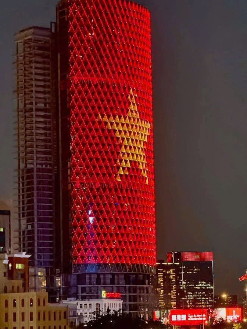 Biểu tượng cờ đỏ sao vàng rực rỡ trên các tòa cao tầng thuộc trung tâm thành phố.