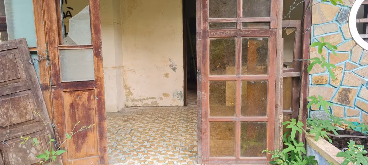 Mặt tiền với khung cửa đã rơi rụng, bạc màu, kính vỡ từng mảng lớn.