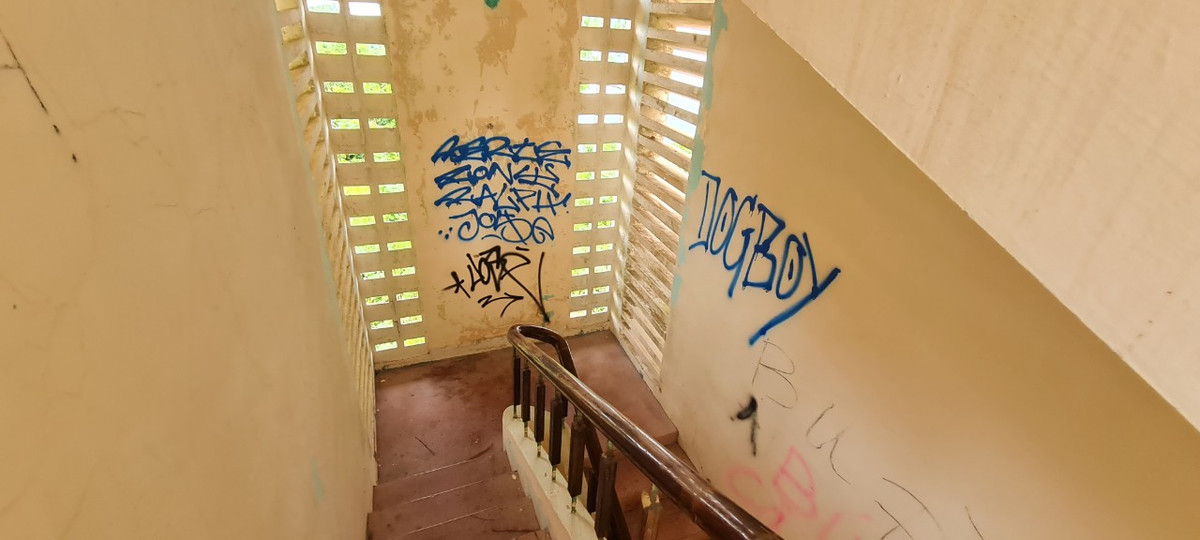 Cầu thang nhỏ hẹp dẫn lên tầng 2 với những bức tường bị vẽ bậy chi chít.