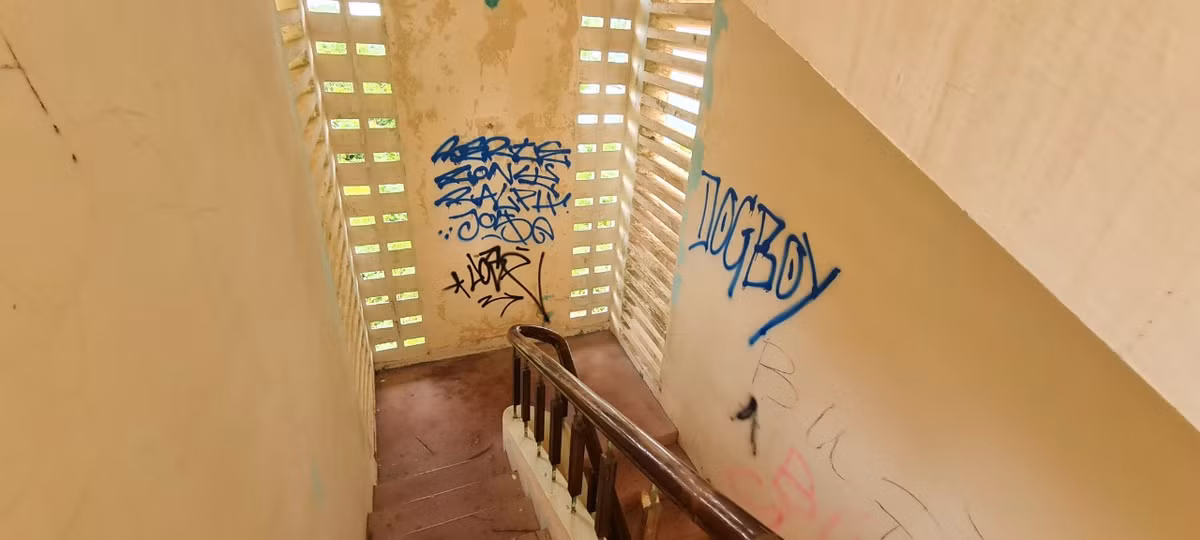 Cầu thang nhỏ hẹp dẫn lên tầng 2 với những bức tường bị vẽ bậy chi chít.