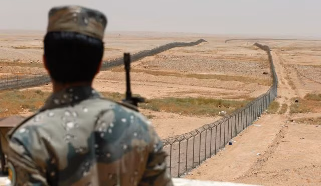 Một lính biên phòng Ả Rập Saudi đứng gác gần một hàng rào biên giới ngăn cách với Iraq.