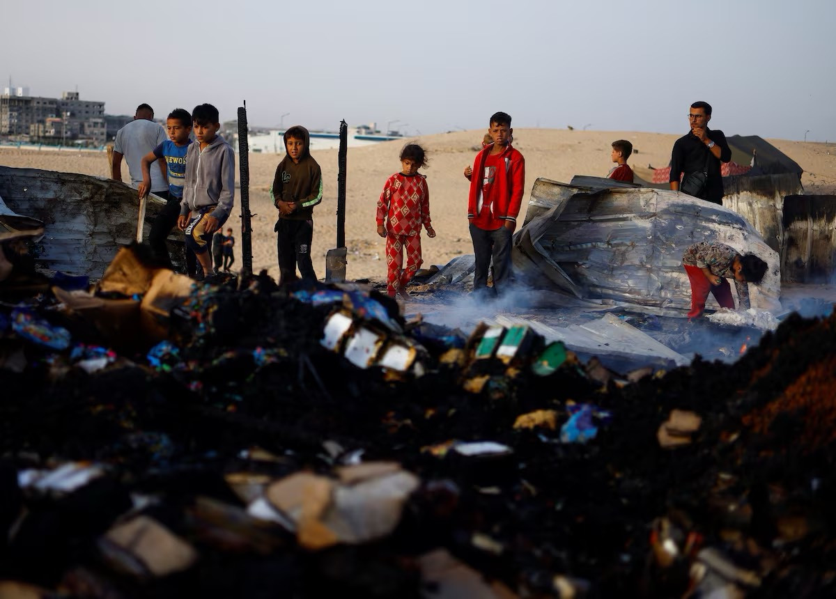 Những đứa trẻ người Palestine nhìn lại hậu quả của cuộc không kích trong khi đang tìm kiếm đồ ăn.