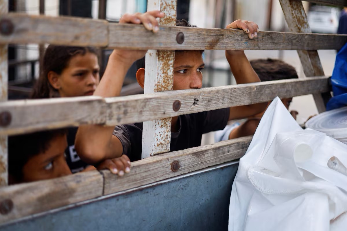 Trẻ em Palestine hướng mắt nhìn vào chiếc xe chở thi thể của những người thiệt mạng.