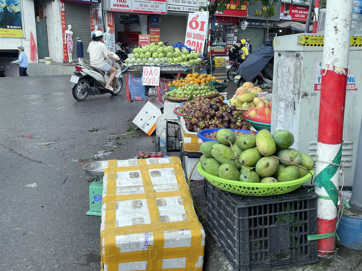 Tại khu vực chợ Ngã Tư Sở (quận Thanh Xuân), nhiều xe đạp, xe máy chở bán hoa, quả tập kết ngay khu vực đường lưu thông hoặc bày bán chắn ngang vỉa hè.
