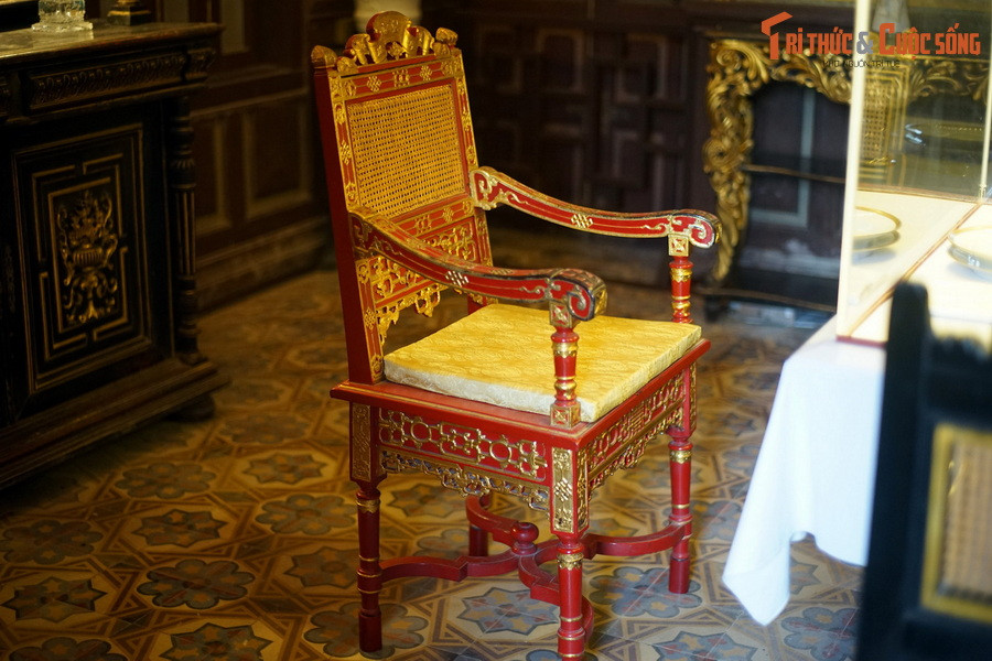 Một chiếc ghế sơn son thiếp vàng, chạm khắc tinh xảo theo kiểu cung đình được đặt trong phòng ăn.