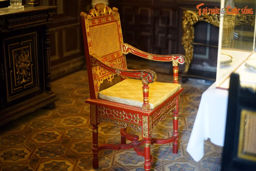 Một chiếc ghế sơn son thiếp vàng, chạm khắc tinh xảo theo kiểu cung đình được đặt trong phòng ăn.