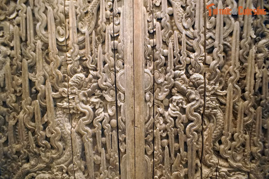 Khi khép lại, hai cánh cửa tạo thành một bức phù điêu hoàn chỉnh khắc họa đề tài “lưỡng long mẫu tử chầu nguyệt” rất sinh động. Mật độ trang trí dày đặc khiến mặt gỗ nhìn từ xa huyền ảo như gấm vóc.