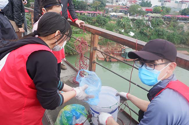 Để hỗ trợ người dân thả cá nhanh hơn mà không cần di chuyển xuống phía chân cầu, nhiều sinh viên tình nguyện đã có mặt để hỗ trợ và nhắc nhở người dân "chỉ thả cá không thả túi nilon".