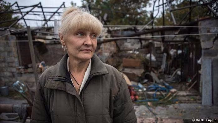 Cô Svetlana Zavadenko đứng trước ngôi nhà của mình ở Spartak. Sau khi được mọi người cứu ra khỏi đống nhà đổ nát do bị trúng đạn pháo, cô đã bị gãy 6 sương sườn và rách một lá phổi. Ảnh DW