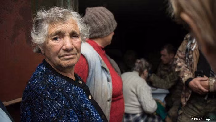 Các cư dân ở Zhovanka đang xếp hàng để khám bệnh. Đội ngũ y bác sĩ sẽ tới thị trấn nằm trên chiến tuyến miền đông Ukraine này mỗi tuần một lần. Ảnh DW