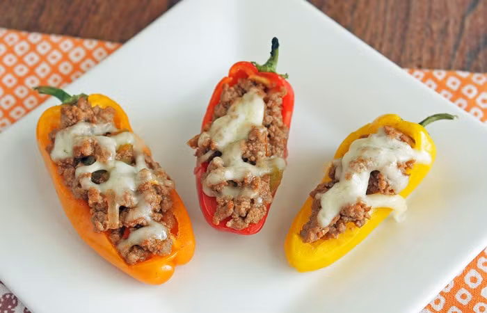 10. Ớt nhồi thịt bò. Xào thịt bò băm nhuyễn với ớt, rau mùi, hành tây xắt nhỏ, bơ, chanh, phô mai trên chảo. Làm sốt phô mai: Cho dầu ô-liu vào chảo và phi hành tây cho đến khi dậy mùi thơm. Cho khoảng 10ml rượu vang trắng, nước dùng gà, bột mì, kem whipping, mù tạt và nêm với muối, tiêu cho vừa miệng. Khi chuẩn bị tắt bếp cho phô mai cheddar vào khuấy đều. Ớt Đà Lạt cắt đôi, bỏ ruột. Nhồi hỗn hợp thịt bò vào trong ớt, rưới sốt phô mai lên và ăn.