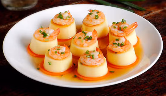 4. Đậu hũ non hấp tôm. Đậu hũ cắt khoanh. Cà rốt cũng gọt vỏ, thái thành khoanh tròn mỏng. Tôm rửa sạch, bóc vỏ. Đặt đậu hũ lên trên miếng cà rốt. Kế đó xếp tôm lên trên mặt rồi cho vào nồi hấp. Nước trong nồi hấp cho vào cỡ 1 chén, sau 5 phút món ăn chín, lấy phần nước còn nóng khuấy với ít bột bắp, thêm xì dầu và dầu mè rồi rưới lên đậu hũ.