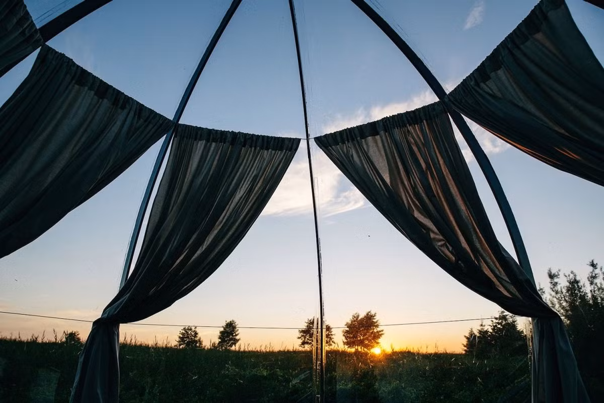 Khung nhà màu đen vững chãi, tương phản với lớp kính chịu lực trong suốt cong cong giúp căn lều chống chọi được với mưa gió, bão táp. Rèm cửa rủ mang không khí lãng mạn cho không gian, đồng thời khuếch tán ánh sáng mặt trời và đảm bảo sự riêng tư.