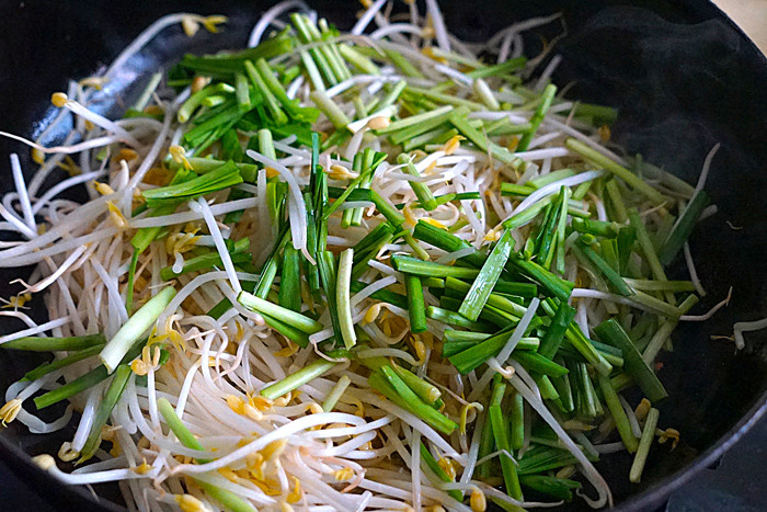 Cho giá đỗ, hẹ xanh vào xào trên lửa lớn. Việc xào trên lửa lớn rất quan trọng, đây được xem là mẹo xào giá đỗ giòn ngon.