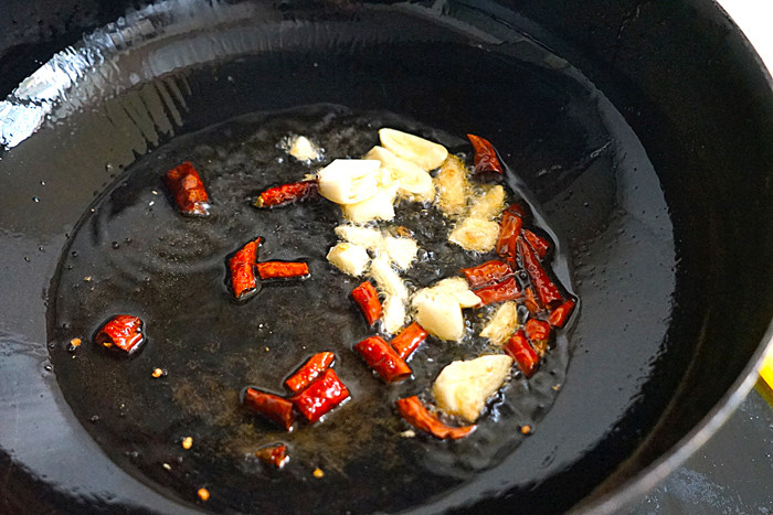 Đun nóng chảo rồi cho dầu ăn vào. Tiếp đó, phi thơm tỏi, ớt khô chừng nửa phút. Bước này rất quan trọng bởi nó quyết định hương vị món ăn.