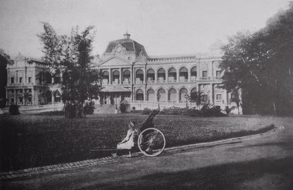 Một phụ nữ ngồi trong khuôn viên Dinh Toàn quyền Sài Gòn, nay là dinh Thống nhất.