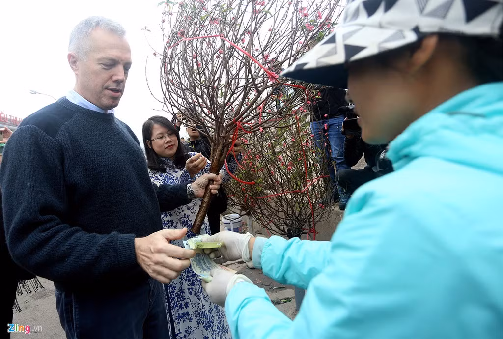 Ông dừng lại mua một cành đào với giá 600.000 đồng. Đại sứ vui vẻ chụp ảnh và trò chuyện với người bán. Theo chia sẻ của chị, năm nay giá đào tăng cao vì thời tiết ấm trước Tết.
