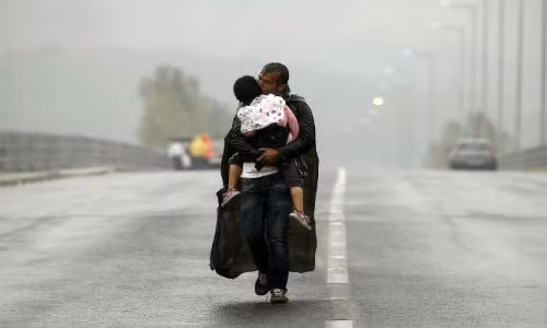 Bức ảnh cảm động về tình phụ tử. Người cha tị nạn Syria bế và hôn con gái khi đang đi trên đường tới biên giới với Macedonia giữa trời mưa tuyết lạnh giá ngày 10/9/2015.