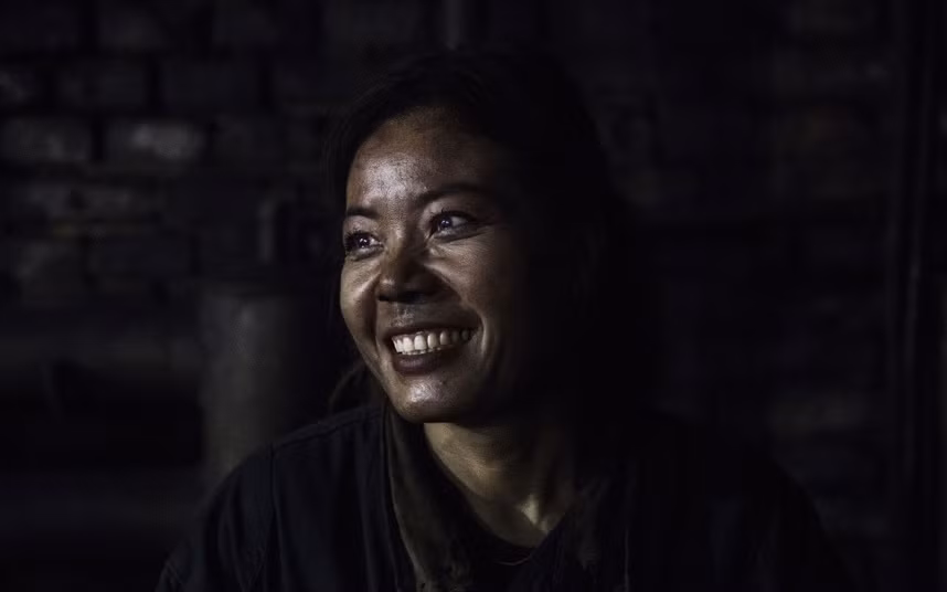 Nữ công nhân mỉm cười khi đang làm công việc phân loại than.