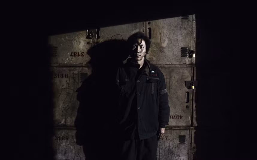 Một thợ mỏ đứng trước tủ đồ sau khi kết thúc ca làm việc của anh.