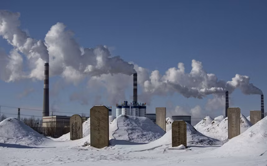 Những nấm mộ bên trong một nghĩa trang ở Sơn Tây. Phía sau là một nhà máy năng lượng chạy bằng than đá đang hoạt động.