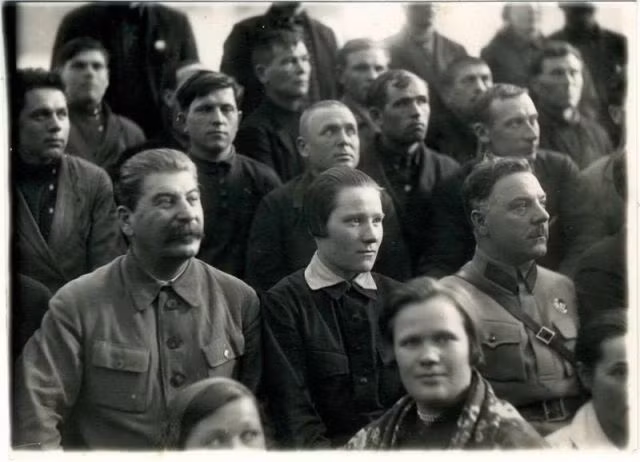 Nhà lãnh đạo Liên Xô ngồi cùng với mọi người và chăm chú theo dõi một sự kiện.