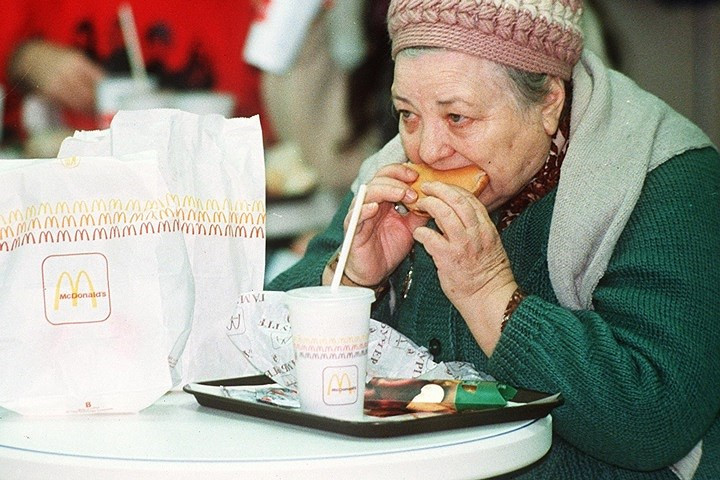 Một phụ nữ đứng tuổi ăn bánh hamburger vào ngày khai trương nhà hàng McDonald đầu tiên ở Moscow, vào ngày 31/1/1990. Ảnh: AP.