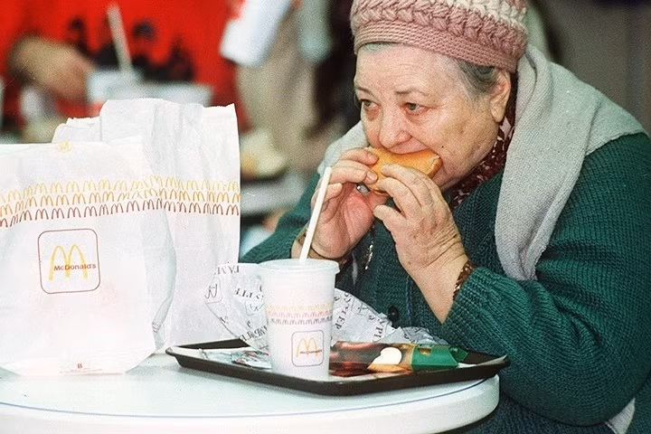 Một phụ nữ đứng tuổi ăn bánh hamburger vào ngày khai trương nhà hàng McDonald đầu tiên ở Moscow, vào ngày 31/1/1990. Ảnh: AP.