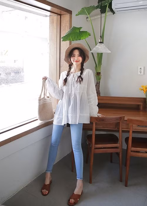 Các bạn gái sẽ có diện mạo bay bổng nữ tính khi diện áo sơ mi cách điệu buộc dây cổ với tông trắng ngọt ngào để mix cùng quần skinny jean và các phụ kiện xinh yêu như dép lê, mũ cói và túi cói.