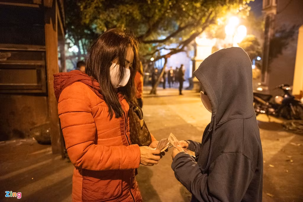 Chị Vân Hương lì xì cho con trai. "Chúc con năm mới học giỏi, nghe lời bố mẹ và thật khỏe mạnh", chị Hương nói với con. Chị cho biết việc đi đền, chùa, phủ thời điểm chuyển giao năm mới đã trở thành thói quen của gia đình.