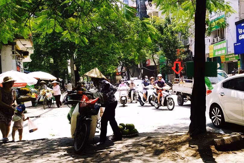 Khi thấy bóng dáng công an đi kiểm tra (mũi tên đỏ), nhiều người bán trái cây vỉa hè trên phố Chùa Láng (quận Đống Đa, TP Hà Nội) vờ thu dọn hàng, chạy lên vỉa hè. Sau khi lực lượng đi qua thì đâu lại vào đó.