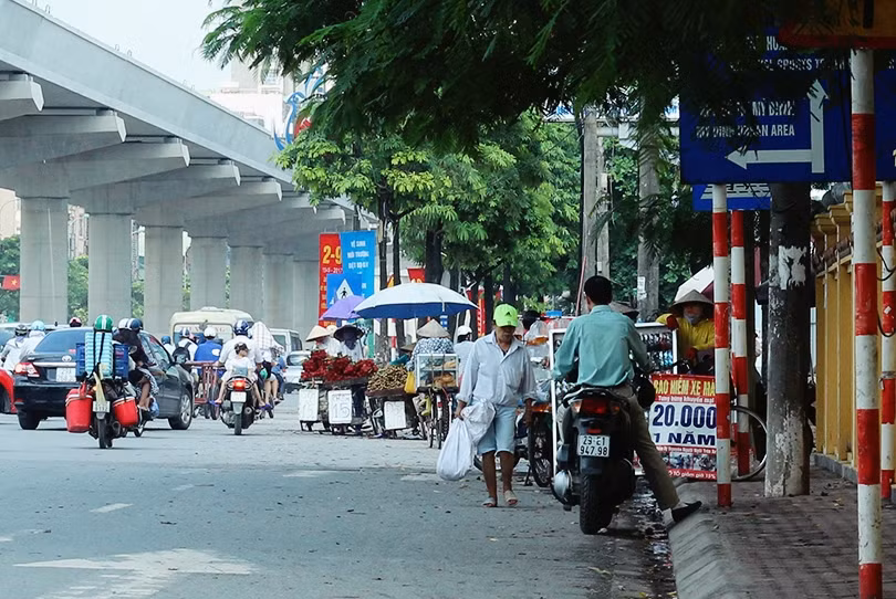 Trên đường Hồ Tùng Mậu (đoạn qua nghĩa trang Mai Dịch và đối diện phía bên trụ sở UBND quận Nam Từ Liêm, TP Hà Nội), những người tham gia giao thông thường xuyên bị hàng chục chiếc xe đạp, xe máy bán hoa quả dựng ra giữa đường chặn lối đi.