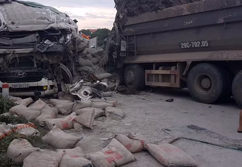 Chiếc xe tải chở xi măng bị biến dạng phần đầu, những bao xi măng chở sau thùng xe bị rơi vương vãi hết xuống đường.