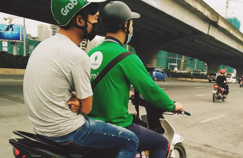 Một nam thanh niên cảm thấy lạnh, ngồi sau xe máy hay tay khoanh vào nhau suýt xoa.