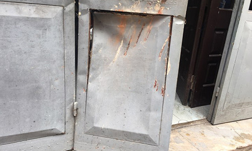 Cánh cửa bị méo mó do bị tường sập đổ đè phải.