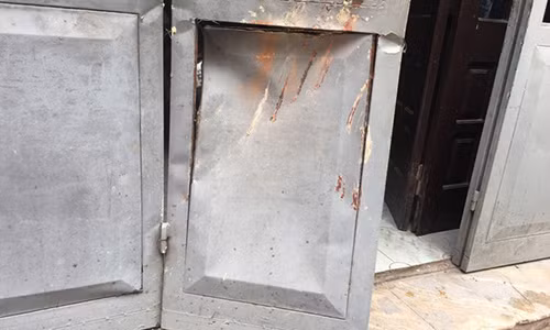 Cánh cửa bị méo mó do bị tường sập đổ đè phải.