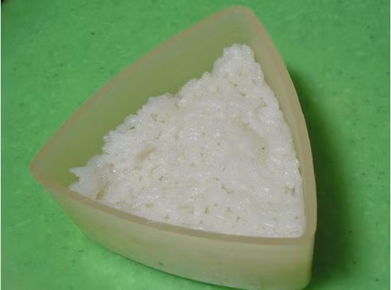 Sau đó, dồn 1 lớp cơm dẻo và nén xuống dưới. Lưu ý trước khi dồn cơm thì nên phết 1 lớp dầu mè quanh khuôn để lúc đổ ra không bị bết dính.