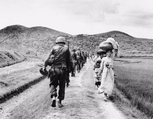 Lính bộ binh Mỹ hành quân vào khu vực sông Nakdong ở Hàn Quốc, trong khi ngược hướng với họ là những người đi chạy nạn.