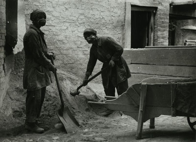 Hai nữ công nhân xúc cát làm việc chăm chỉ tại nhà máy chế tạo thủy tinh ở Lancashire.