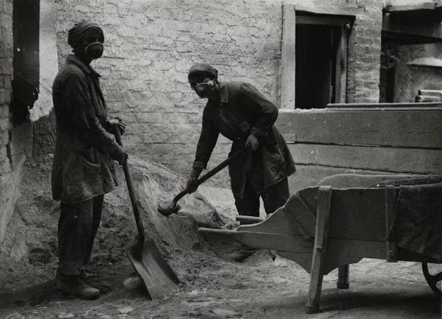 Hai nữ công nhân xúc cát làm việc chăm chỉ tại nhà máy chế tạo thủy tinh ở Lancashire.