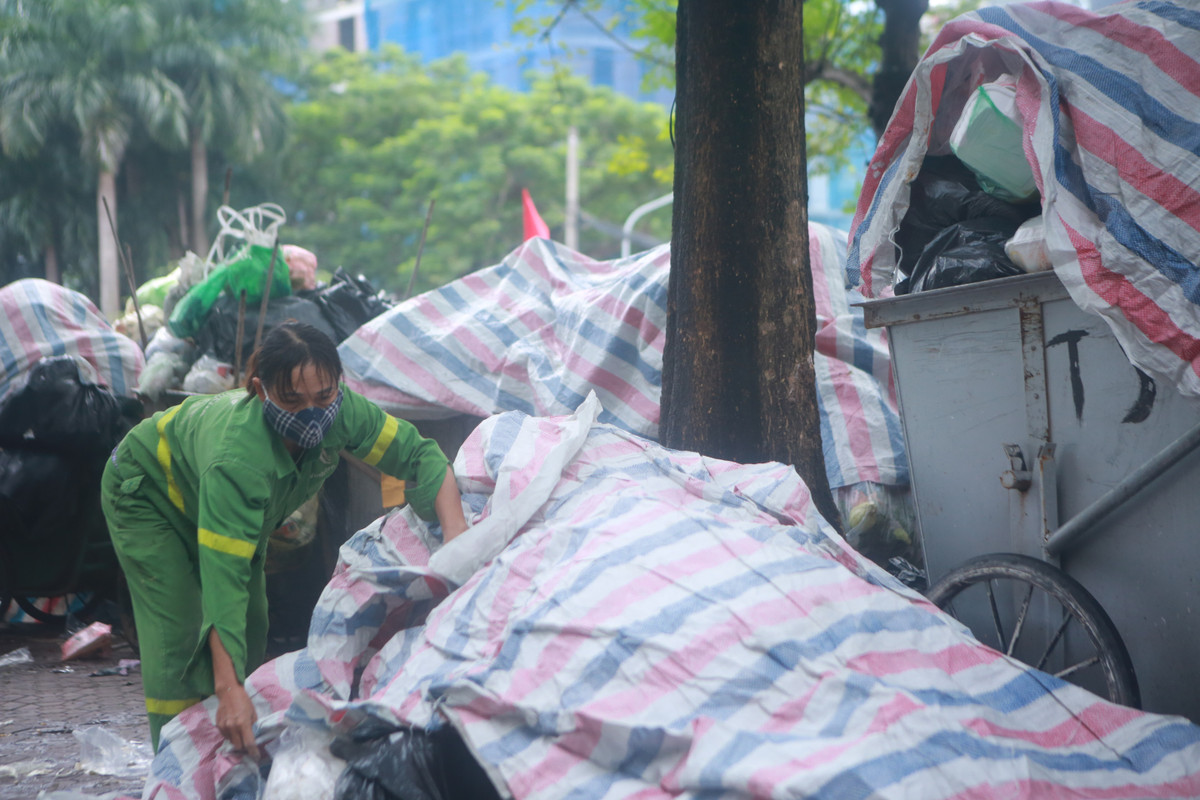 Để hạn chế mùi hôi bốc lên, nhân viên vệ sinh môi trường đã phải dùng bạt lớn phủ lên các xe rác.