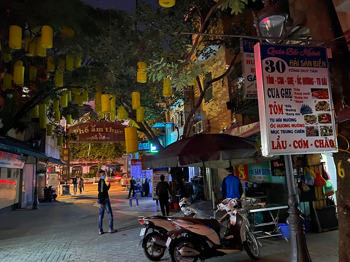 Các hàng quán mở hé cửa để khách ngồi bên trong, bên ngoài có nhân viên đứng trông xe và làm nhiệm vụ cảnh giới.