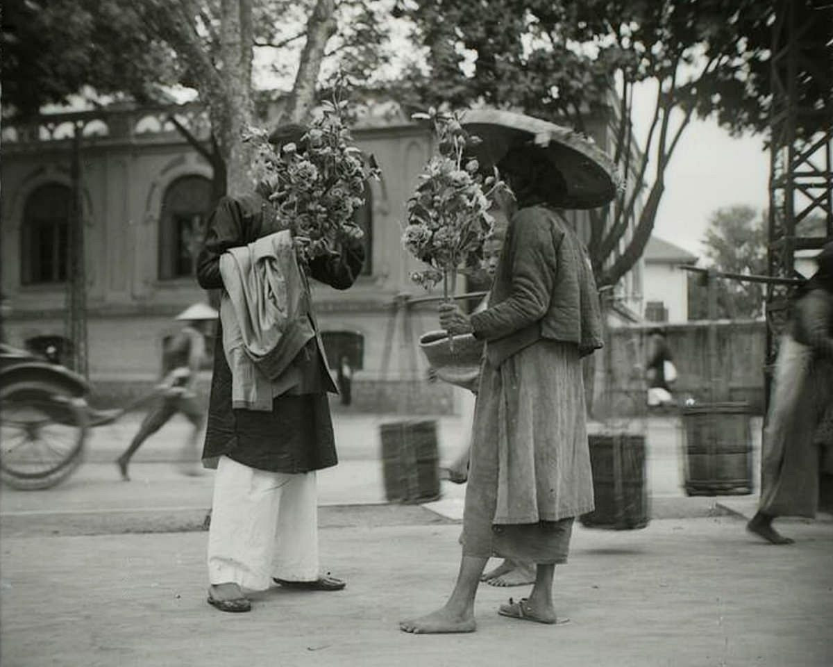 Hà Nội thập niên 1920 - Người bán hoa giấy trên phố Hàng Bạc, gần ngày Tết.