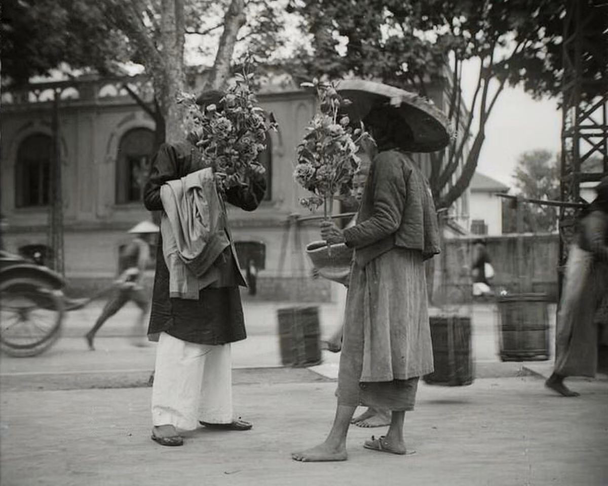 Hà Nội thập niên 1920 - Người bán hoa giấy trên phố Hàng Bạc, gần ngày Tết.